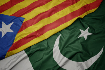 waving colorful flag of pakistan and national flag of catalonia.