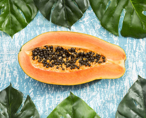 Half cut papaya fruit with monstera leaves