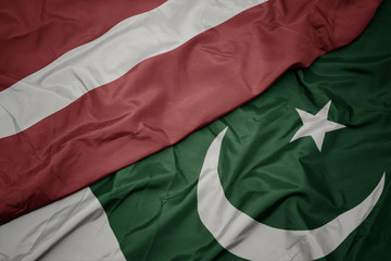 waving colorful flag of pakistan and national flag of latvia.