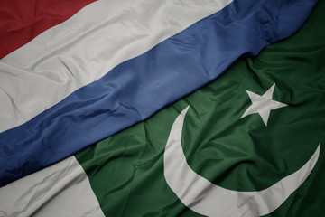 waving colorful flag of pakistan and national flag of netherlands.