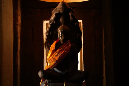 Ancient buddha statue in an old temple in golden traditional clothes.