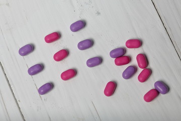 Dragee for refreshment of breath. Different color. Lay in rows. On a coral background.