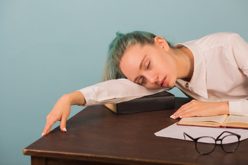 Obraz premium beautiful young woman sleeping at a table with books