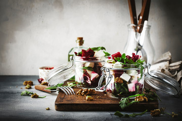 Beet and cheese healthy salad with arugula and walnuts, trendy salad jar, gray kitchen table, place for text, selective focus