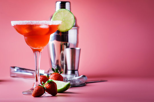 Strawberry red margarita alcoholic cocktail with tequila, liqueur, berries, lime juice, sugar and ice, pink background, copy space