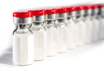 Glass medical vials of biotech drugs. With red caps. Selective focus.