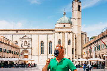 Obraz premium horse man standing in the middle of the historic square of Ascoli Piceno in Italy, eating a fried olive stuffed with pork, named oliva ascolana. It is a famous italian street food.