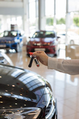 Dealer woman holding keys to a new car. Modern and prestigious vehicles.