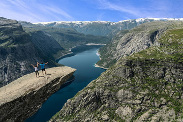 Norway: couple on Trolltunga rock above Ringedalsvatnet mountain lake - famous Norwegian hiking tourist landmark.