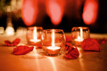 Three small candles with rose petals for events red background