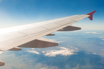 Aircraft wing on the clouds, flies on the mountains background