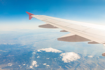 Aircraft wing on the clouds, flies on the mountains background