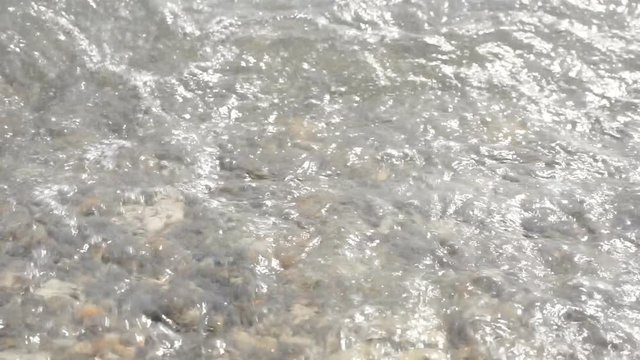 Coastal waves on a pebble beach.Pebbles and waves. clear water near the shore with pebbles at the bottom. Travel and vacation season.1920X1080 Full Hd.