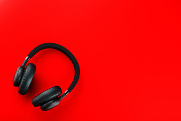 Black wireless headphones on a red background. Overhead, isolated professional-grade headphones for DJs and musicians