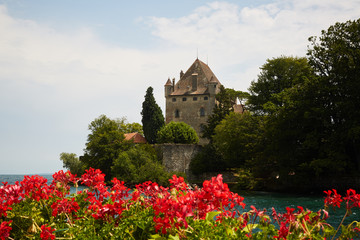 Castle in yvoire with red flowers in front