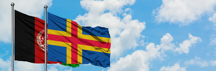 Afghanistan and Aland Islands flag waving in the wind against white cloudy blue sky together....