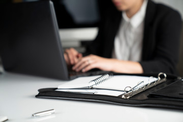 Fototapeta premium Young businesswoman sitting on her workplace and looking at laptop in the office.