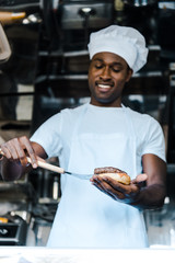 selective focus of handsome afrian american man holding spatula while preparing burger