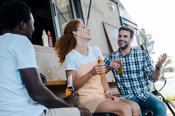selective focus of happy man gesturing near multicultural friends