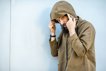 Portrait of a mysterious and weird man wearing hoodie coat on the blue background