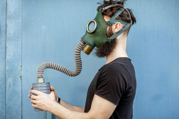 Portrait of a man with gas mask on the blue background. Concept of poor ecology, air pollution and...