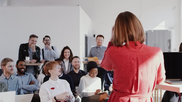 Back view coach business woman giving a talk at modern office seminar event for multiethnic team slow motion RED EPIC.