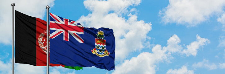 Afghanistan and Cayman Islands flag waving in the wind against white cloudy blue sky together....
