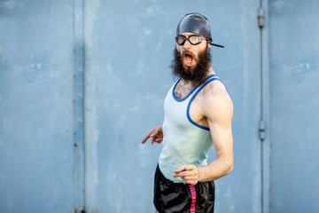 Portrait of a weird, old-fashioned swimmer dressed in 80s style with hat and swimming glasses on the yellow background