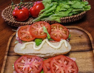 Delicious looking submarine sandwiches preparation, made with ham, salami, provolone cheese,...