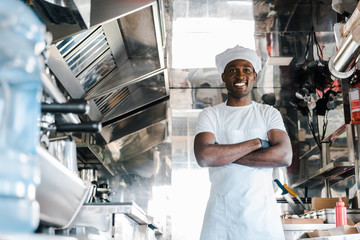 selective focus of happy african american chef standing with crossed arms in food truck