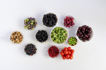 top view of bowls with fresh berries of cherry, raspberry, strawberry, blackberry, gooseberry, mulberry and grape diet