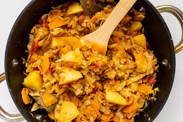 top view of vegetable stew  mix in cauldron on a color surface with a wooden stick