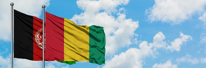 Afghanistan and Guinea flag waving in the wind against white cloudy blue sky together. Diplomacy...
