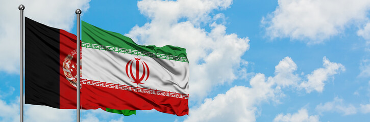 Afghanistan and Iran flag waving in the wind against white cloudy blue sky together. Diplomacy...