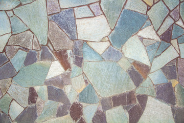 Decorative texture of concrete fencing from stones of different sizes, shapes and colors in the form of a mosaic.