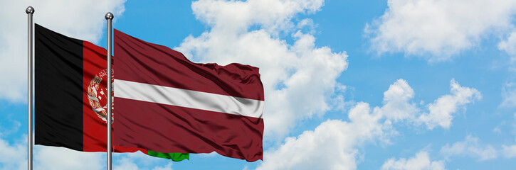 Afghanistan and Latvia flag waving in the wind against white cloudy blue sky together. Diplomacy...