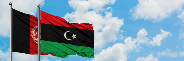 Afghanistan and Libya flag waving in the wind against white cloudy blue sky together. Diplomacy...