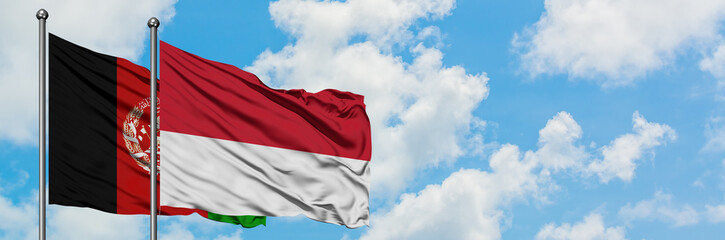 Afghanistan and Monaco flag waving in the wind against white cloudy blue sky together. Diplomacy...