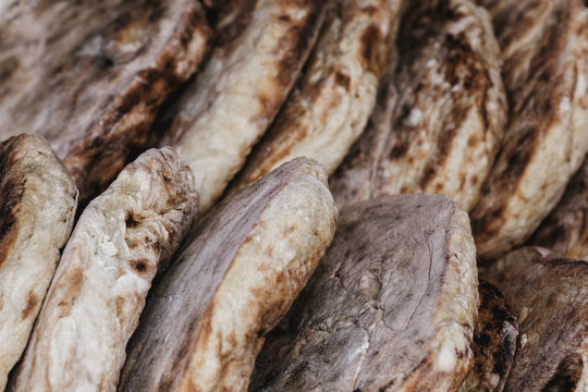 "Bolo do caco" is a flat, circular bread, shaped like a cake and thus called "bolo", portuguese word for 'cake'. It is traditionally cooked on a "caco", a flat basalt stone slab.