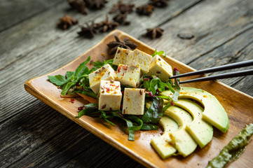 Talerz tofu z świeżymi warzywami i avocado na talerzu i drewnianym stole - 285518620