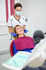 young female dentist with happy mature woman patient at clinic