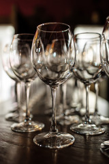 empty wine glasses. Beautiful new glasses for wine from glass stand in even rows on a wooden table in a restaurant. selective focus