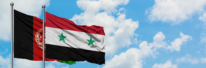 Afghanistan and Syria flag waving in the wind against white cloudy blue sky together. Diplomacy...