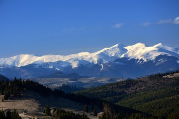 Spring landscape with mountain tops covered with snow