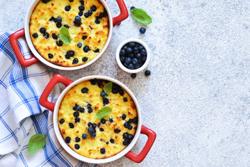 Cottage cheese casserole with blueberries on the kitchen table. Dessert on a stone white background.