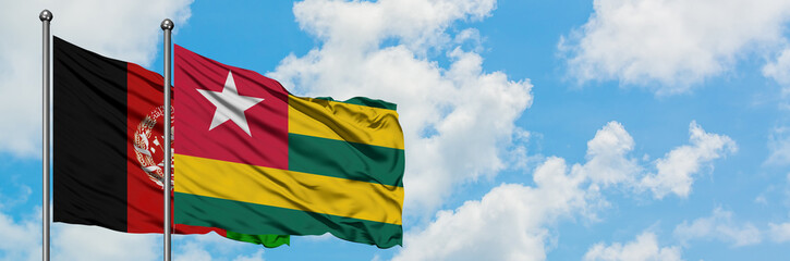 Afghanistan and Togo flag waving in the wind against white cloudy blue sky together. Diplomacy...