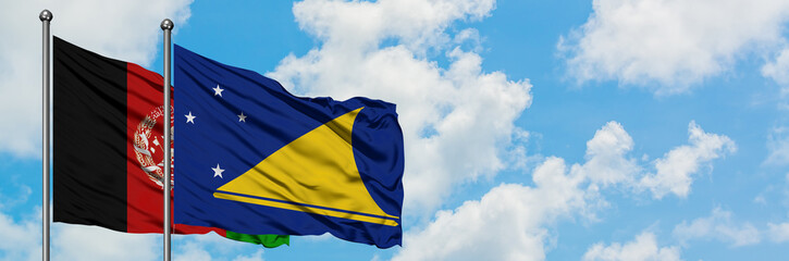 Afghanistan and Tokelau flag waving in the wind against white cloudy blue sky together. Diplomacy...
