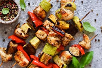 Barbecue of chicken on skewers with vegetables on stone background. Picnic.