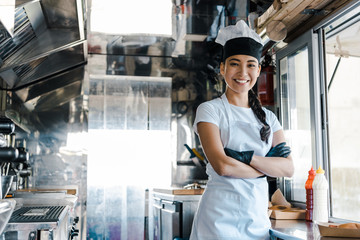 happy asian woman standing with crossed arms in food truck