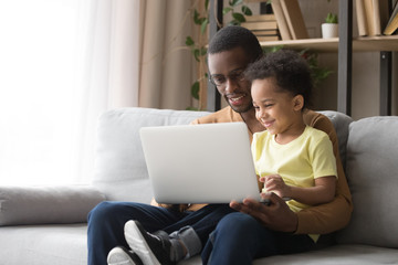 African American father teaching toddler son to use laptop